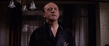 Movie still from “Funeral in Berlin” (1966), directed by Guy Hamilton – An older man wearing a black robe looking to his left; Close Up shot, Low angle