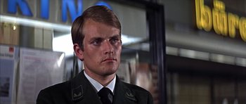 Movie still from “Funeral in Berlin” (1966), directed by Guy Hamilton – A person wearing a suit and tie; Close Up shot, Low angle