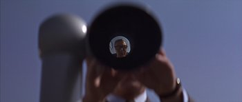 Movie still from “Funeral in Berlin” (1966), directed by Guy Hamilton – A man looking through a telescope at something in the sky; Close Up shot, Low angle