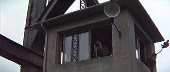 Movie still from “Funeral in Berlin” (1966), directed by Guy Hamilton – A man taking a picture from a window of a building; Wide shot, Low angle