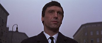 Movie still from “Funeral in Berlin” (1966), directed by Guy Hamilton – A person wearing a suit and tie; Close Up shot, Low angle