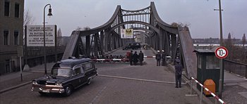 Movie still from “Funeral in Berlin” (1966), directed by Guy Hamilton – A group of people standing on a bridge; Wide shot, High angle