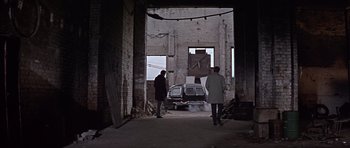 Movie still from “Funeral in Berlin” (1966), directed by Guy Hamilton – Two people are standing in an alley way; Wide shot, High angle