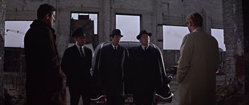 Movie still from “Funeral in Berlin” (1966), directed by Guy Hamilton – A group of men standing next to each other in suits; Wide shot, Low angle
