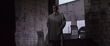 Movie still from “Funeral in Berlin” (1966), directed by Guy Hamilton – A man standing in front of a brick wall; Wide shot, Low angle