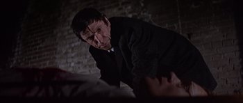 Movie still from “Funeral in Berlin” (1966), directed by Guy Hamilton – A man standing in a dark room looking at something; Close Up shot, Low angle