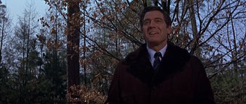 Movie still from “Funeral in Berlin” (1966), directed by Guy Hamilton – A man in a brown coat standing next to a tree; Close Up shot, Low angle