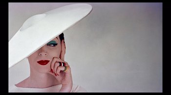 Movie still from “Funny Face” (1957), directed by Stanley Donen – A person wearing a hat and holding a cell phone; Close Up shot, Low angle