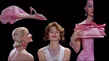 Movie still from “Funny Face” (1957), directed by Stanley Donen – A woman in a white dress and some pink shoes; Medium shot, Low angle