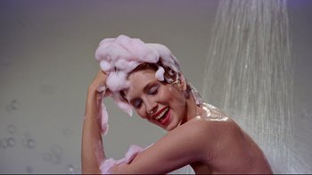 Movie still from “Funny Face” (1957), directed by Stanley Donen – A woman is washing her hair in the shower; Medium shot, Low angle