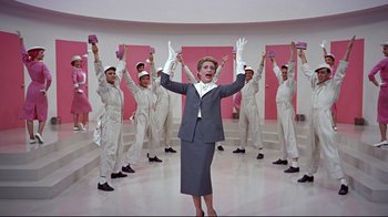 Movie still from “Funny Face” (1957), directed by Stanley Donen – A group of men in white suits and a woman in a gray suit; Wide shot, Low angle