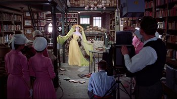 Movie still from “Funny Face” (1957), directed by Stanley Donen – A woman in a yellow dress standing in a room; Wide shot, Low angle