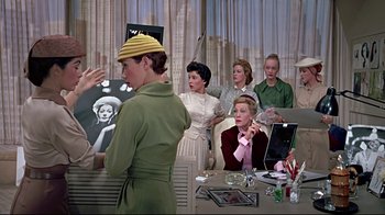 Movie still from “Funny Face” (1957), directed by Stanley Donen – A group of women sitting around a table; Medium shot, Low angle