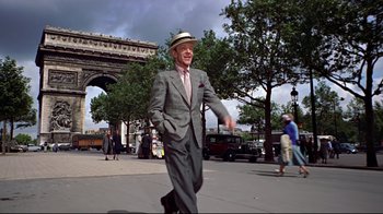 Movie still from “Funny Face” (1957), directed by Stanley Donen – An older man in a suit and hat walking down the street; Wide shot, Low angle