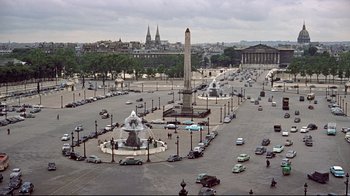 Movie still from “Funny Face” (1957), directed by Stanley Donen – An aerial view of a city with a lot of cars parked in it; Extreme Wide shot, High angle