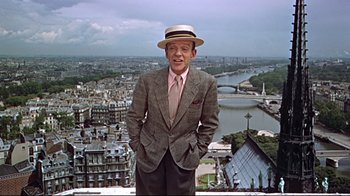 Movie still from “Funny Face” (1957), directed by Stanley Donen – A man in a suit and hat standing in front of a city; Medium shot, Low angle