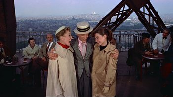Movie still from “Funny Face” (1957), directed by Stanley Donen – A man and two women standing next to each other; Medium shot, High angle