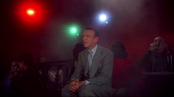 Movie still from “Funny Face” (1957), directed by Stanley Donen – A man in a suit and tie sitting on a chair; Medium shot, Low angle