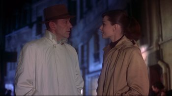 Movie still from “Funny Face” (1957), directed by Stanley Donen – A man and a woman standing next to each other in front of a building; Close Up shot, Over the shoulder angle