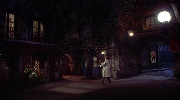 Movie still from “Funny Face” (1957), directed by Stanley Donen – A man in a white lab coat walking down a street; Extreme Wide shot, High angle