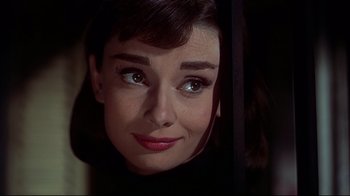 Movie still from “Funny Face” (1957), directed by Stanley Donen – A woman's face in a dark room; Close Up shot, Over the shoulder angle