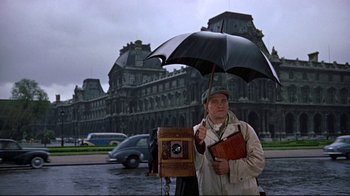 Movie still from “Funny Face” (1957), directed by Stanley Donen – A man holding an umbrella while standing in the rain; Medium shot, Low angle