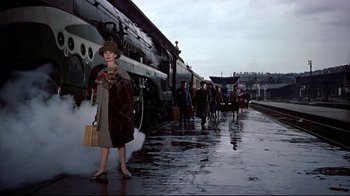 Movie still from “Funny Face” (1957), directed by Stanley Donen – A woman standing in front of a train on a train track; Wide shot, Low angle