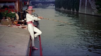 Movie still from “Funny Face” (1957), directed by Stanley Donen – A man in white suit and hat holding a fishing rod; Wide shot, Low angle