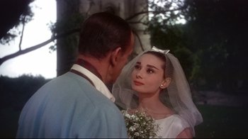 Movie still from “Funny Face” (1957), directed by Stanley Donen – A man and a woman in wedding attire looking at one another; Close Up shot, Over the shoulder angle