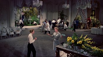 Movie still from “Funny Face” (1957), directed by Stanley Donen – A group of people standing in a room; Wide shot, High angle
