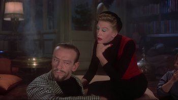 Movie still from “Funny Face” (1957), directed by Stanley Donen – A man and a woman sitting next to each other on a couch; Medium shot, Over the shoulder angle