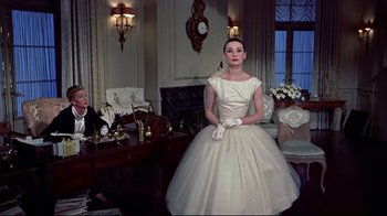 Movie still from “Funny Face” (1957), directed by Stanley Donen – A woman in a white dress in a living room; Medium shot, Low angle