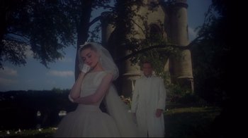 Movie still from “Funny Face” (1957), directed by Stanley Donen – A man and a woman dressed in white standing in front of a castle; Medium shot, Low angle