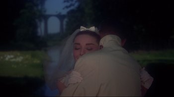 Movie still from “Funny Face” (1957), directed by Stanley Donen – A man and a woman embracing each other in front of trees; Close Up shot, Low angle