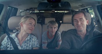 Movie still from “Funny Games” (2007), directed by Michael Haneke – A man and a woman and a child in a car; Medium shot, Over the shoulder angle