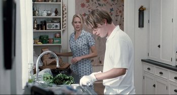 Movie still from “Funny Games” (2007), directed by Michael Haneke – A man and a woman in a kitchen preparing food; Medium shot, Over the shoulder angle