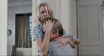 Movie still from “Funny Games” (2007), directed by Michael Haneke – A woman is hugging a young man in a room; Close Up shot, Over the shoulder angle