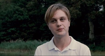 Movie still from “Funny Games” (2007), directed by Michael Haneke – A young man in a white shirt is posing for a picture; Close Up shot, Over the shoulder angle