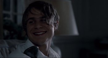 Movie still from “Funny Games” (2007), directed by Michael Haneke – A young man smiles while holding a phone; Close Up shot, Over the shoulder angle