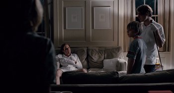 Movie still from “Funny Games” (2007), directed by Michael Haneke – A man sitting on top of a couch next to another man; Wide shot, Over the shoulder angle