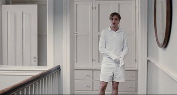 Movie still from “Funny Games” (2007), directed by Michael Haneke – A man standing in front of a white cabinet; Medium shot, Low angle