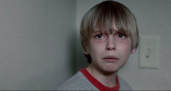 Movie still from “Funny Games” (2007), directed by Michael Haneke – A young boy with a sad look on his face; Close Up shot, Low angle