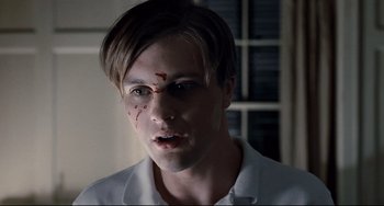 Movie still from “Funny Games” (2007), directed by Michael Haneke – A young man with a blood splatter on his face; Close Up shot, High angle
