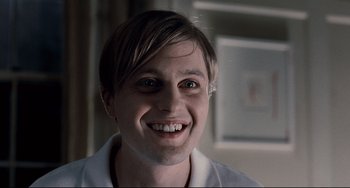 Movie still from “Funny Games” (2007), directed by Michael Haneke – A man with short blonde hair smiling for the camera; Close Up shot, Low angle