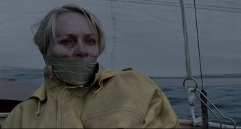 Movie still from “Funny Games” (2007), directed by Michael Haneke – A woman with a duct taped mouth on a boat; Close Up shot, High angle