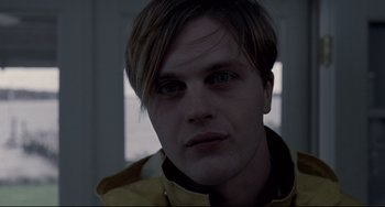 Movie still from “Funny Games” (2007), directed by Michael Haneke – A person wearing a yellow jacket; Close Up shot, Low angle