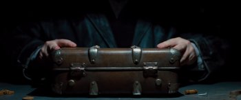 Movie still from “G-Force” (2009), directed by Hoyt Yeatman – A person is holding an old trunk in front of a table; Extreme Close Up shot, Overhead angle