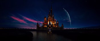 A large castle with lights on the front of it at night time