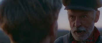 Movie still from “Gallipoli” (1981), directed by Peter Weir – A man with a hat looking at another man with a hat; Close Up shot, Over the shoulder angle