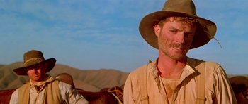 Movie still from “Gallipoli” (1981), directed by Peter Weir – A man with a hat on and a horse in the background; Close Up shot, Low angle